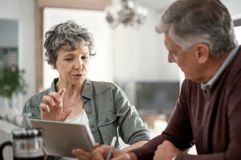 mature couple talking while using a digital tablet to learn about annuity riders