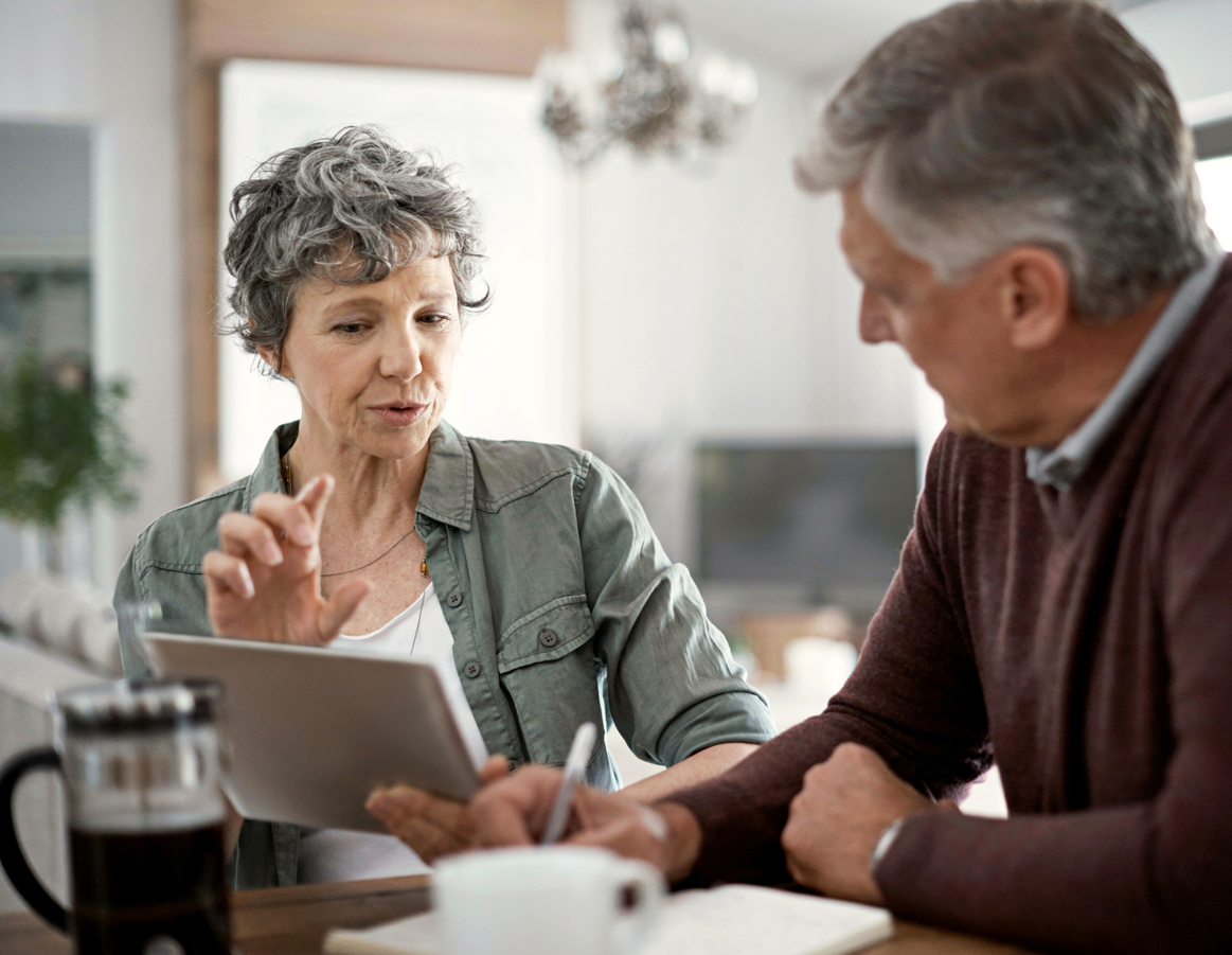 mature couple talking while using a digital tablet to learn about annuity riders